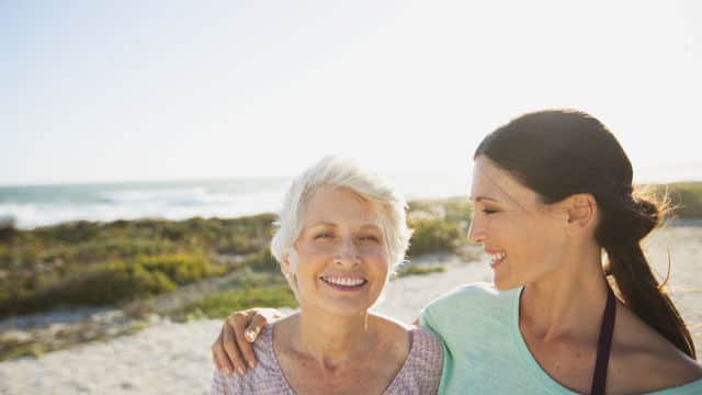 mother and daughter smiling while walking at the beach