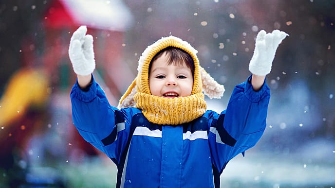 Niño dentando sonrie mientras nieva