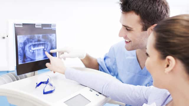 a dentist and a dentist assitant viewing an x-ray chart