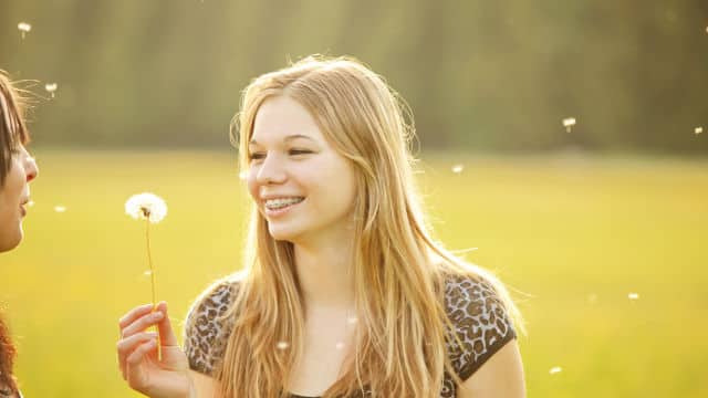 two women smiling holding a dandelion