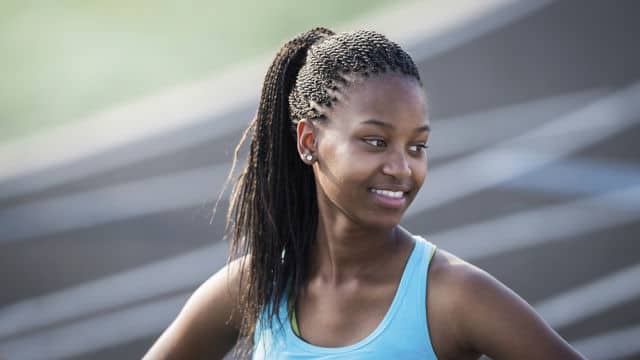 a woman smiling at an outdoor track field