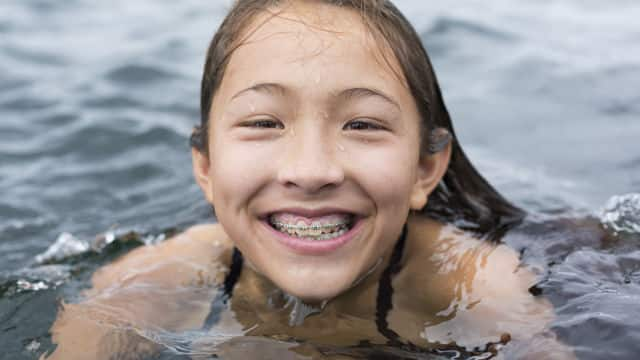 Niña con brackest sonrie en el agua 