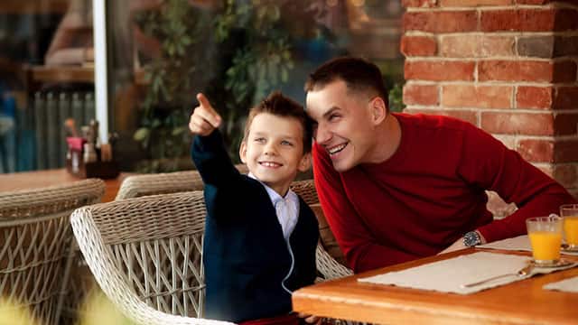 a young boy smiling pointing and the father smiling looking