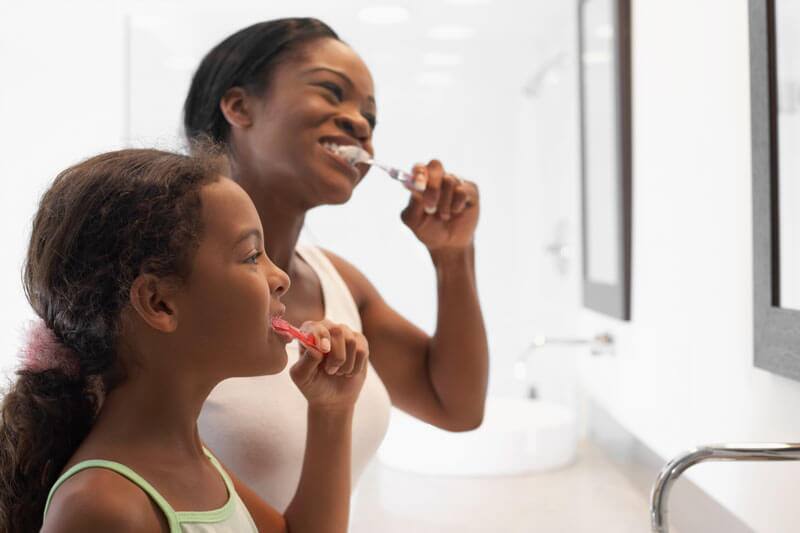 Madre e hijas felices lavándose los dientes