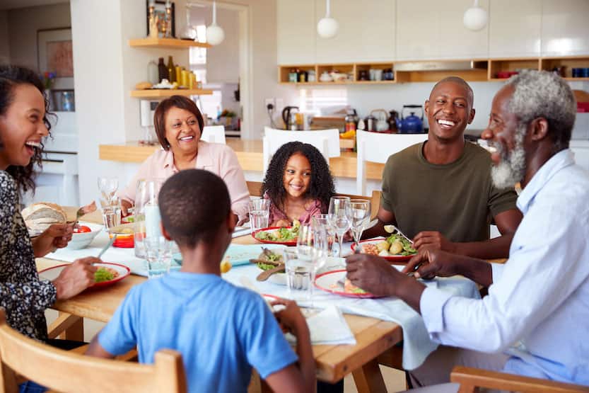 Multi-Generation Family Sitting Around Table At Home Enjoying Meal Together
