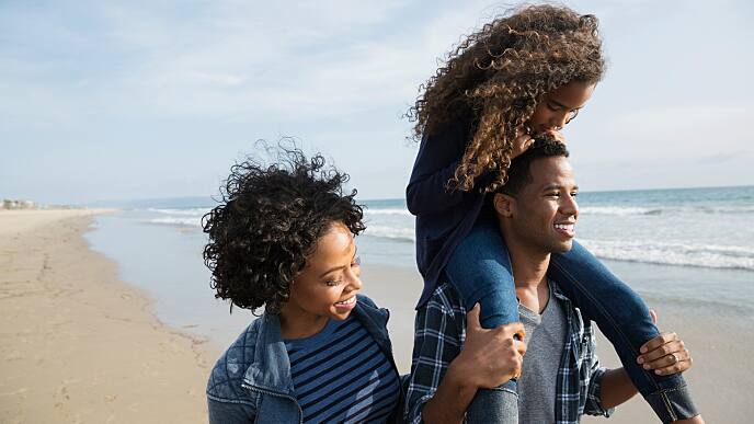 Hija con sus padres felices en la playa