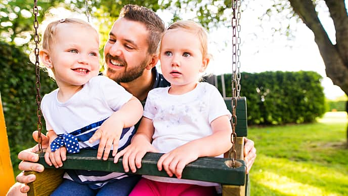 Padre jugando con sus hijas en el parque