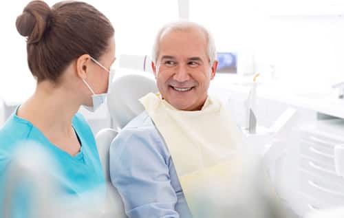 Mujer dentista profesional interactuando con paciente adulto mayor