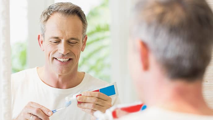 man smiling applying Colgate toothpaste
