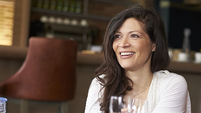 Mujer sonriendo mientras come en restaurante