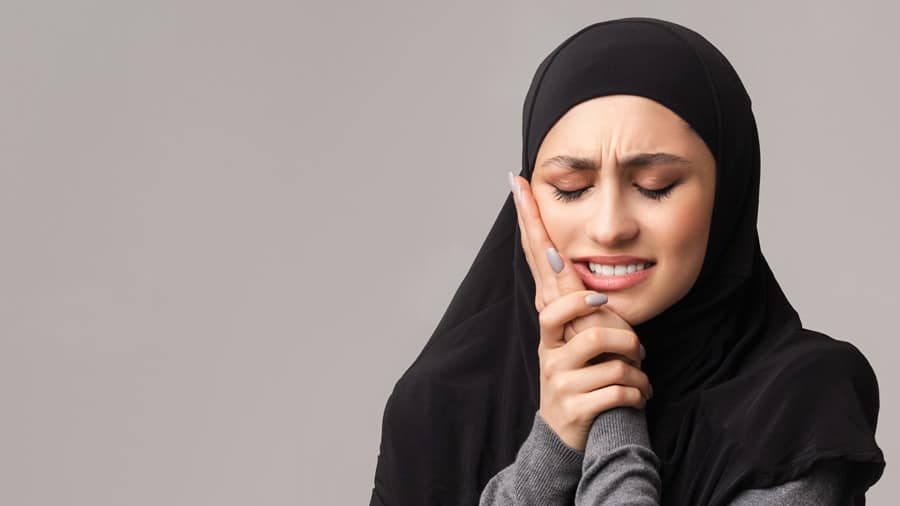 woman with toothache holding her face