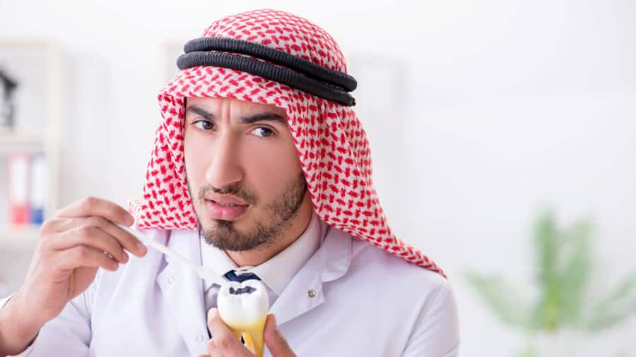 young dentist showing a plastic tooth with cavity