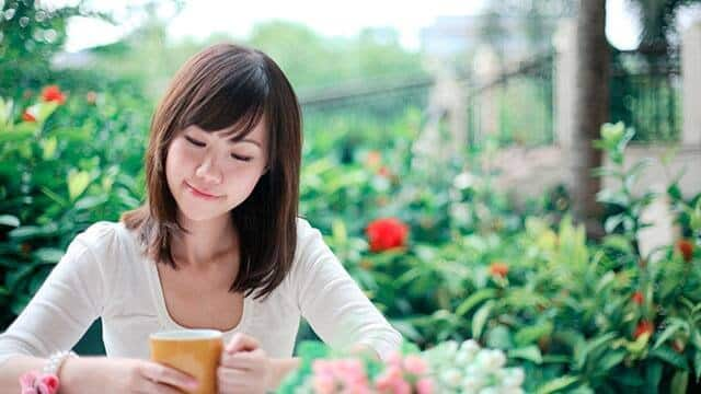 a young woman is drinking tea in a garden