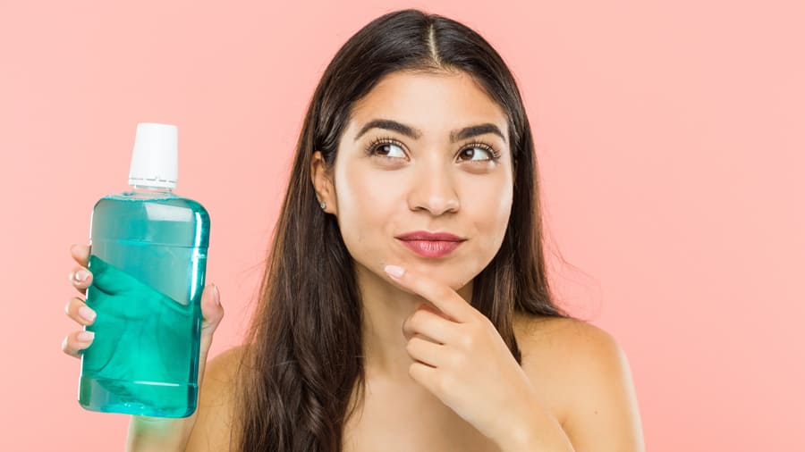 A young woman thinking about the benefits of an antibacterial mouthwash