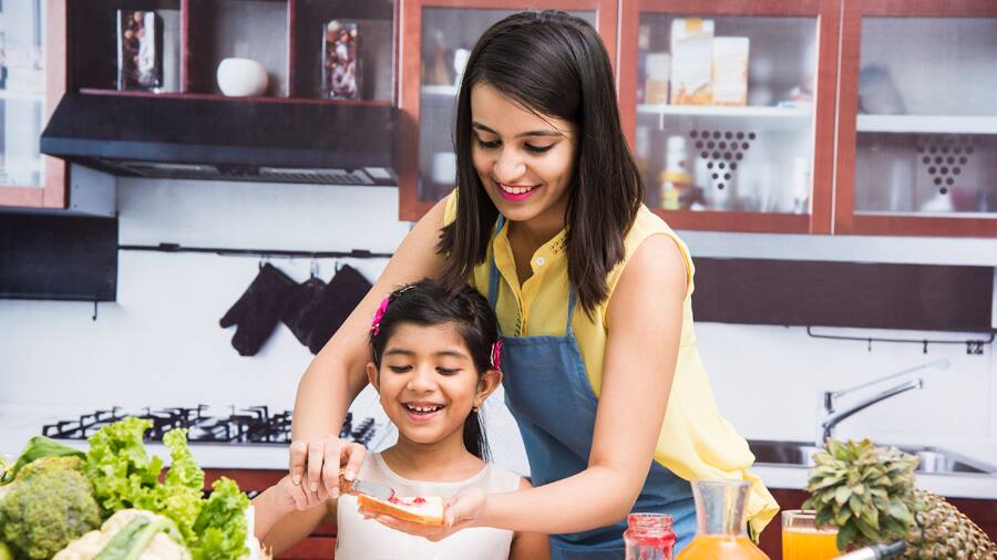 a mother and daughter spreading jam onto a bread