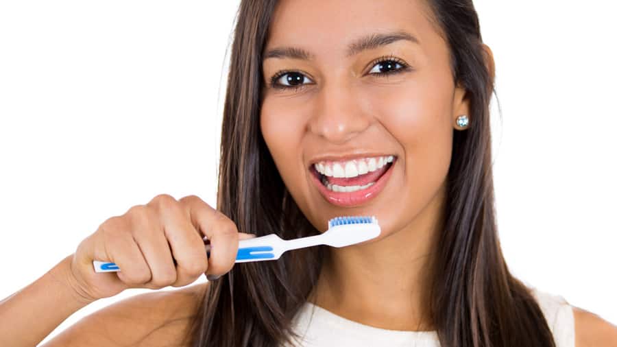 A woman brushing her teeth with teeth whitening toothpaste