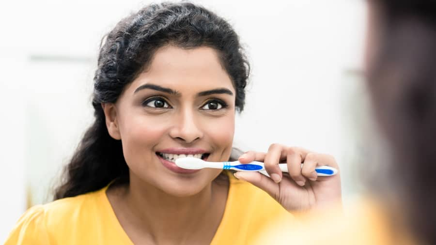 Young woman using toothpaste as home remedies for tooth sensitivity