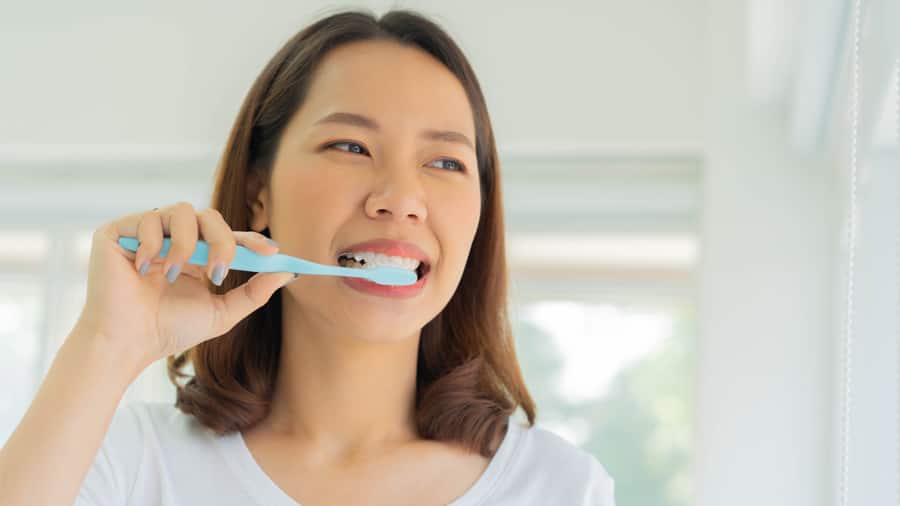 A Woman  Brushing Her Teeth To Maintain Oral Health