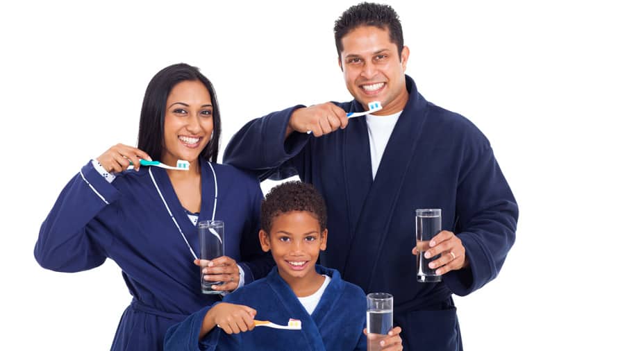 man, woman, and a boy brushing with Colgate toothbrush and toothpaste