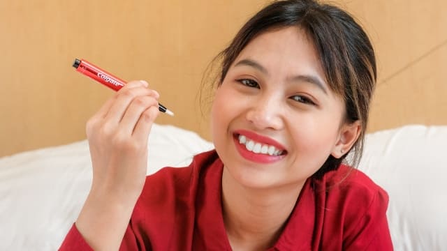 Smiling woman holding a Colgate teeth whitening pen