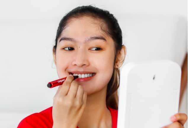 Woman using the Colgate teeth whitening pen