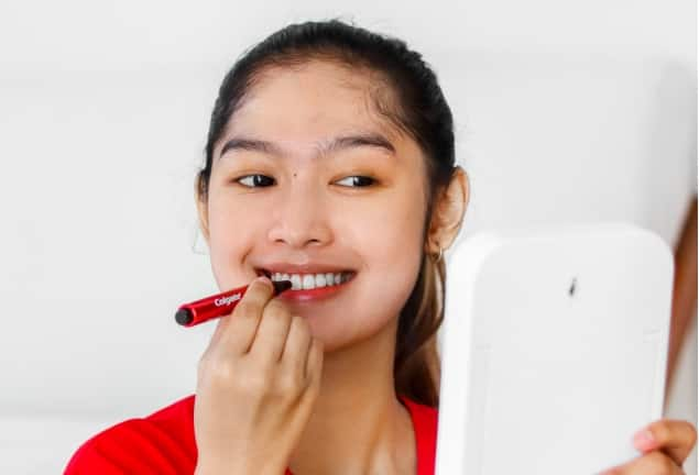 Smiling woman holding a small cup of mouthwash