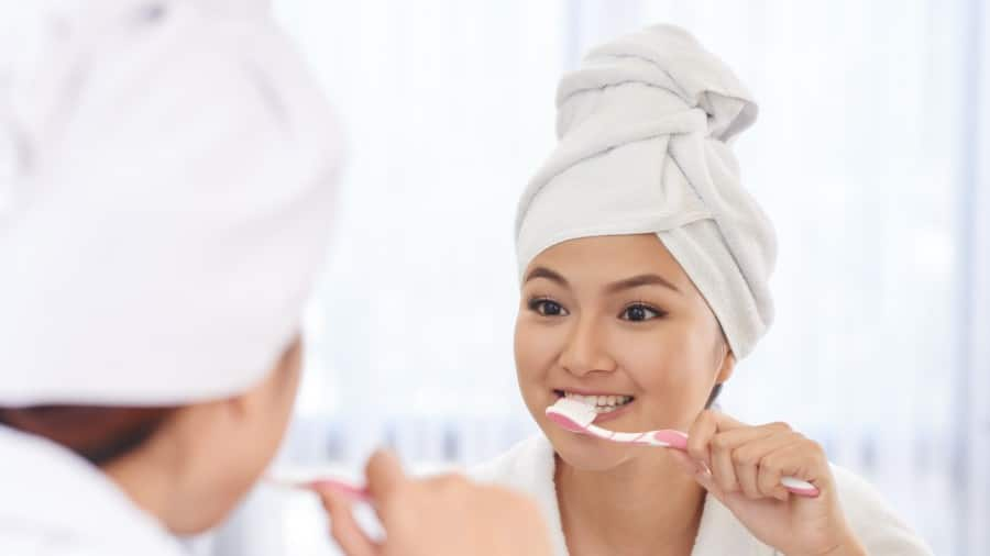 a mother and a daughter brushing their teeth with Colgate tootbrush