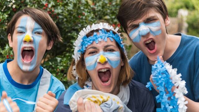 Familia alentando con los colores de la bandera argentina en la cara