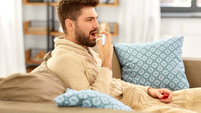 Hombre joven usando spray bucal