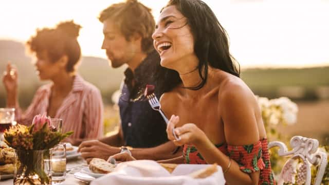Mujer con sonrisa blanca disfrutando con amigos en una cena al aire libre