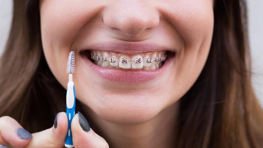 Mujer lavándose los dientes con brackets