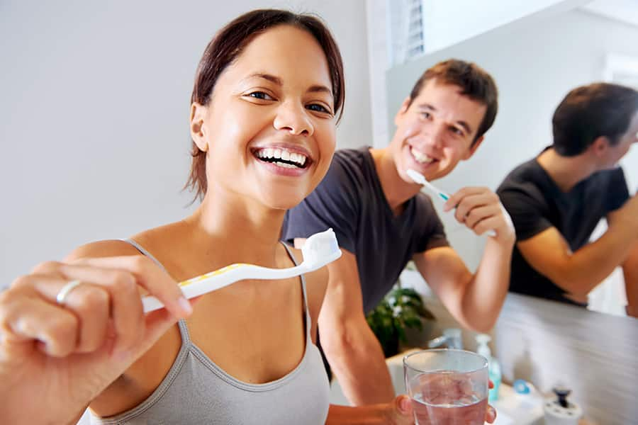 Pareja sonriente lavándose los dientes