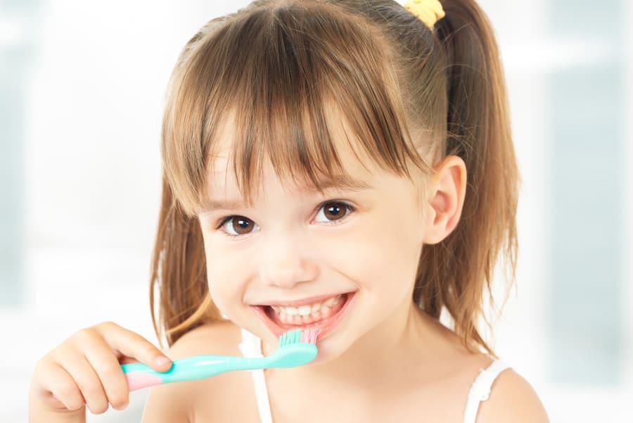 Niña pequeña feliz cepillándose los dientes