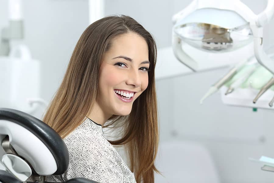 Mujer joven sonriendo en cita odontológica