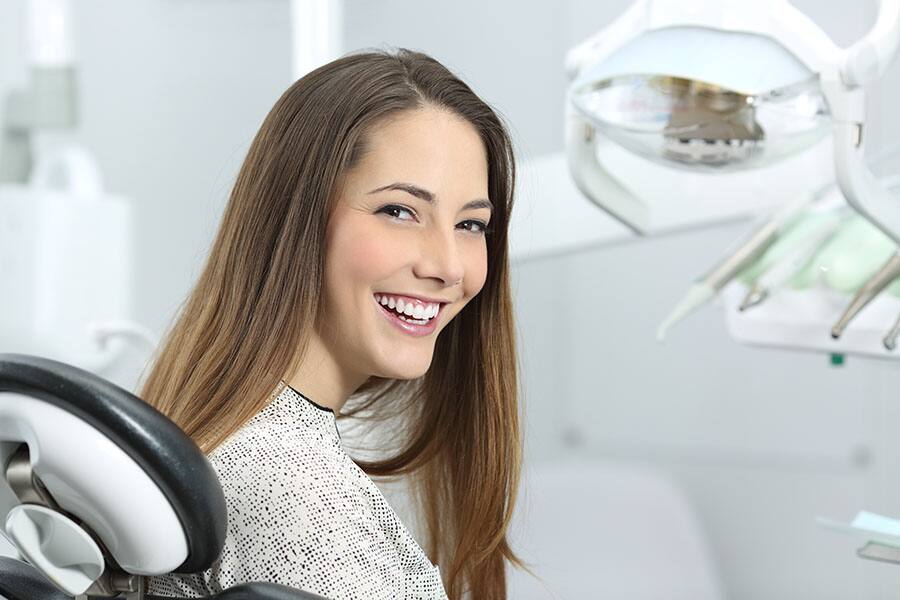 Mujer joven sonriendo en cita odontológica