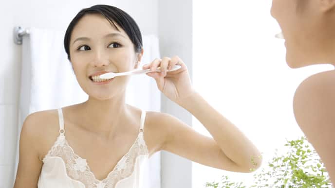 Women brushing teeth with stannous fluoride toothpaste for strong enamel protection