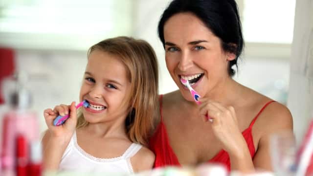 Mamá e hija se cepillan los dientes 
