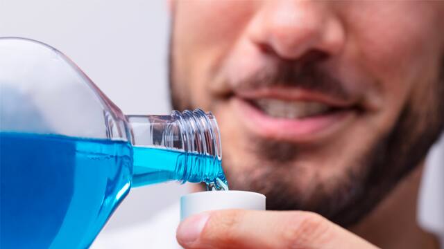 Man pouring mouthwash into a cap Close-up of a man pouring mouthwash into a cap
