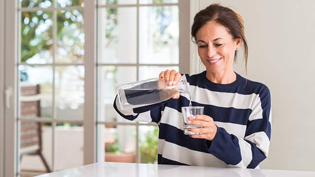 Mujer sonriente tomando agua