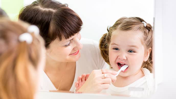 Una madre cepilla los dientes de un niño