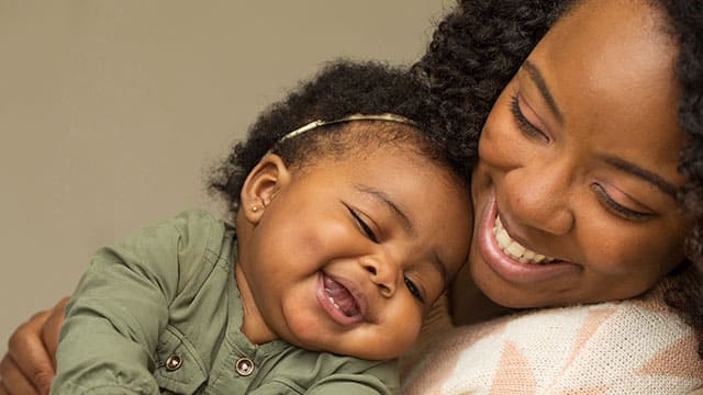 A mother and daughter indoors Mother and baby daughter smiling and hugging