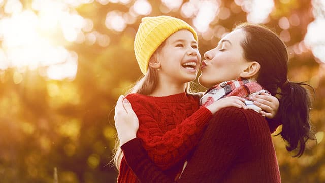 Smiling child and mother outdoors in autumn