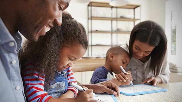 Parents And Children Drawing On Whiteboards At Table