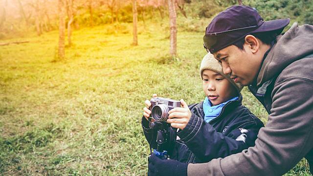 father teaching son how to use a camera