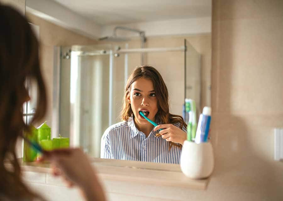 https://www.colgate.com/content/dam/cp-sites/oral-care/oral-care-center/global/article/portrait-of-a-beautiful-woman-brushing-teeth-and-looking-in-the-mirror-in-the-bathroom.jpg