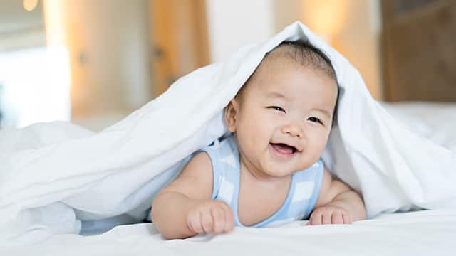 a baby is sitting in bed happyily after white tongue is cured