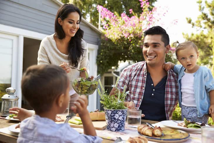 Family At Home Eating Outdoor Meal In Garden Together