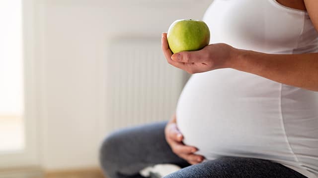 pregnant holding a green apple