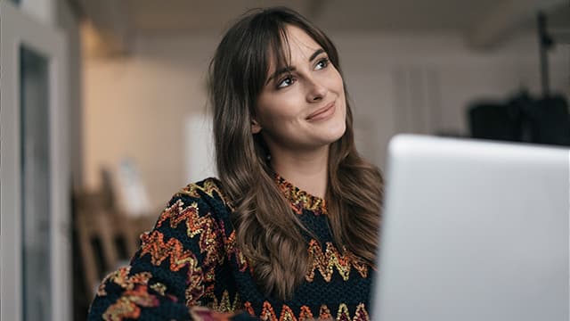 woman sitting in front of laptop smiling away