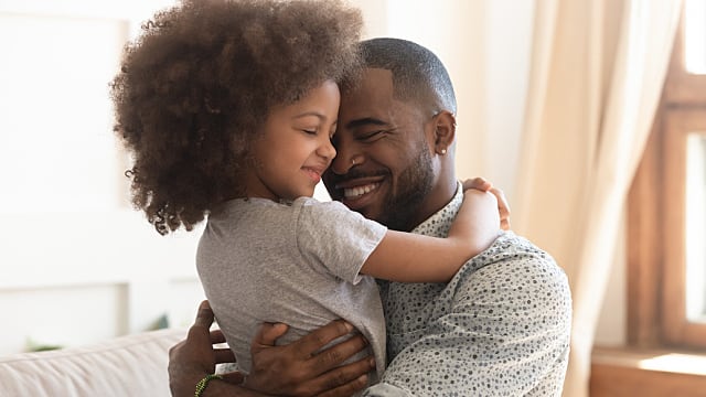 father and daughter are hugging after pulling a loose baby tooth